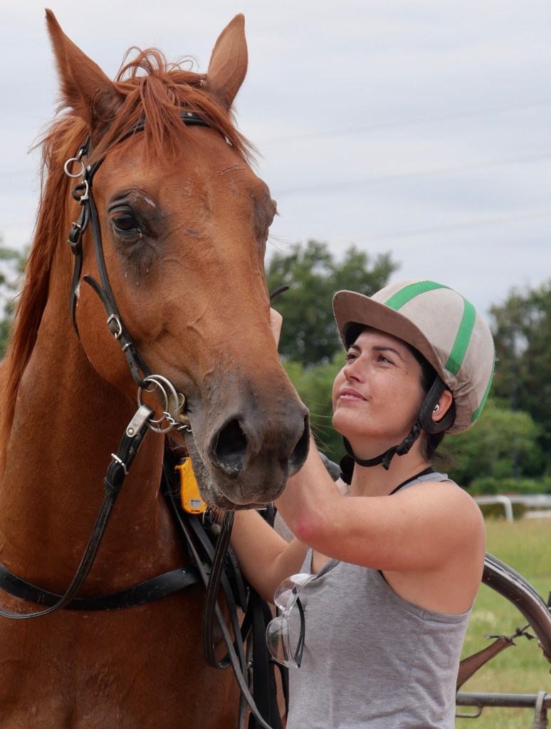 Samantha Vinci, casque sur la tête, auprès d’un cheval alezan.